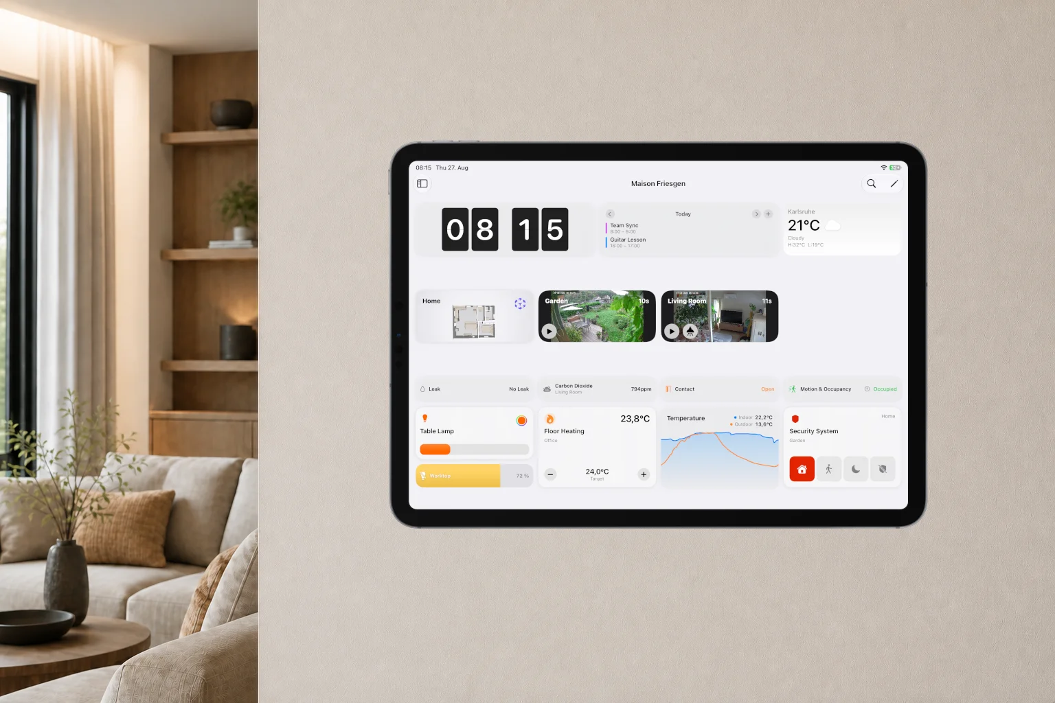 An iPad on a living room wall showing a Controller 10 dashboard with clock, calendar, weather, floor plan, cameras, sensors, lighting, heating, a temperature chart and the security system